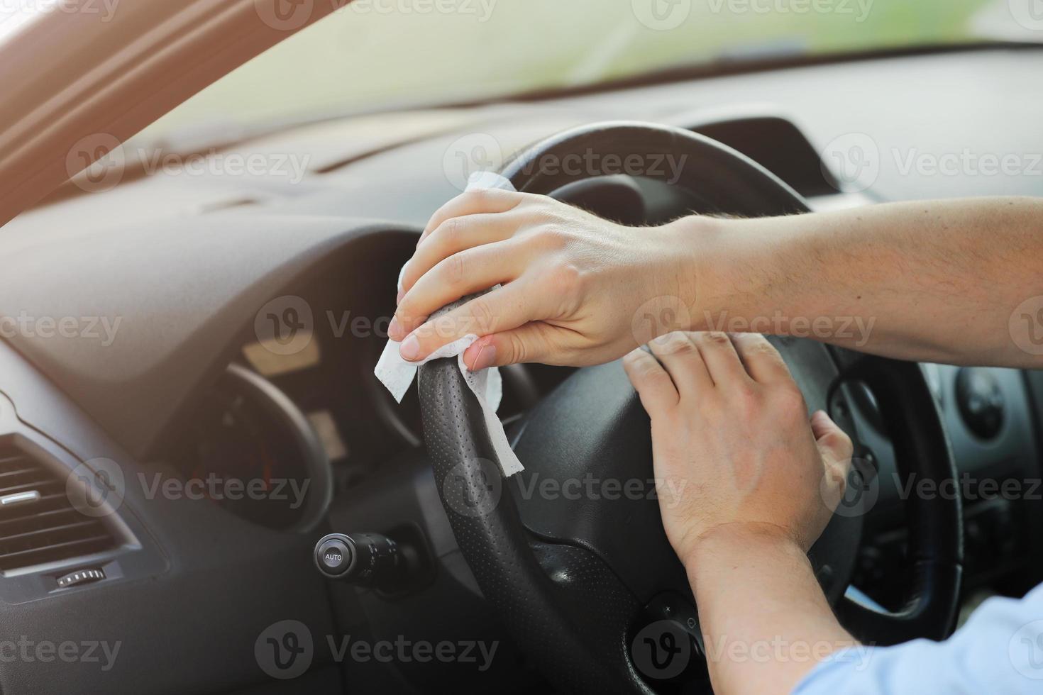 conductor que usa toallitas húmedas para desinfectar el volante de un automóvil contra el virus o la enfermedad del coronavirus. limpieza de autos. enfoque selectivo. foto