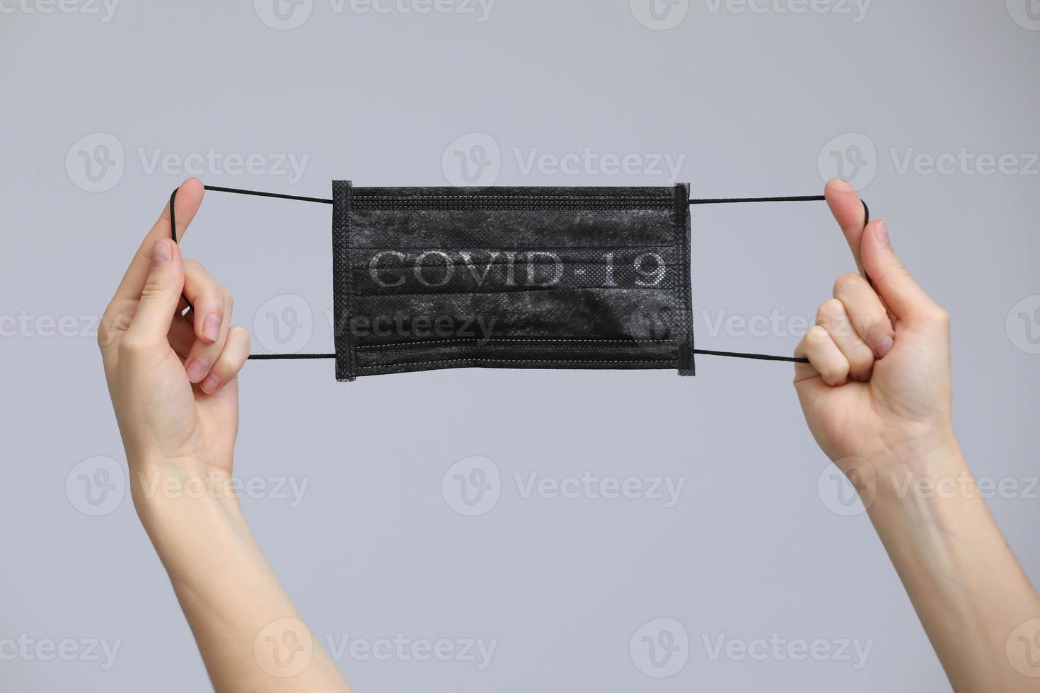 Woman's hands holding a facial medical mask on grey background, close up, copy space, flu epidemic, allergy season, protection against virus - Covid-19 and coronavirus. photo