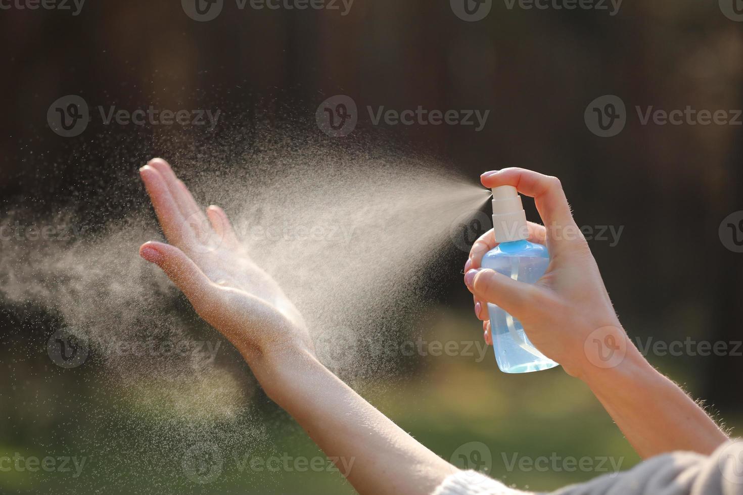 Cerca de las manos de la mujer aplicando spray de alcohol o spray antibacteriano al aire libre para evitar la propagación de gérmenes, bacterias y virus, tiempo de cuarentena, concéntrese en las manos cercanas. coronavirus. foto