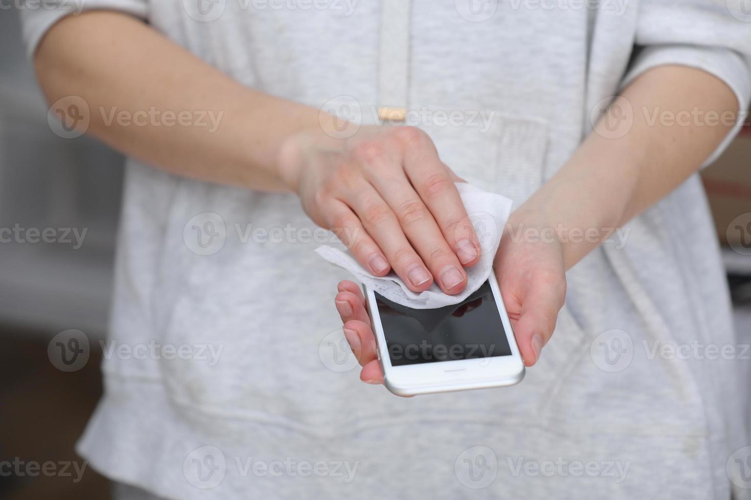 mujer desinfectando teléfono con toallita húmeda antiséptica. servilleta antiséptica para prevenir la propagación de gérmenes, bacterias y coronavirus. prevención contra el coronavirus. prevenir la enfermedad coronavirus después de un lugar público. foto