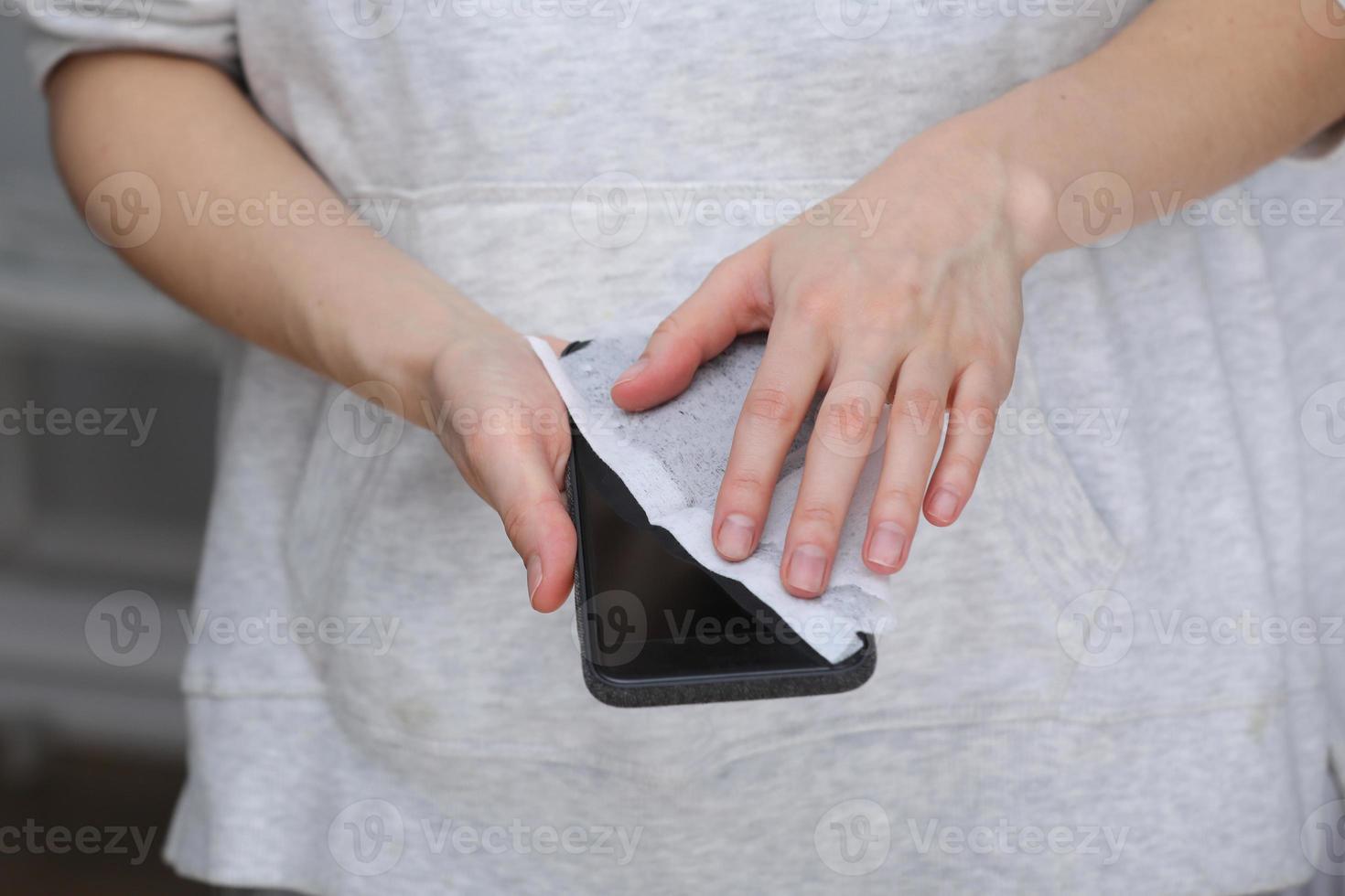 Woman disinfecting phone with antiseptic wet wipe. Antiseptic napkin to prevent spread of germs, bacteria and coronavirus. Coronavirus prevention. Prevent illness coronavirus after public place. photo