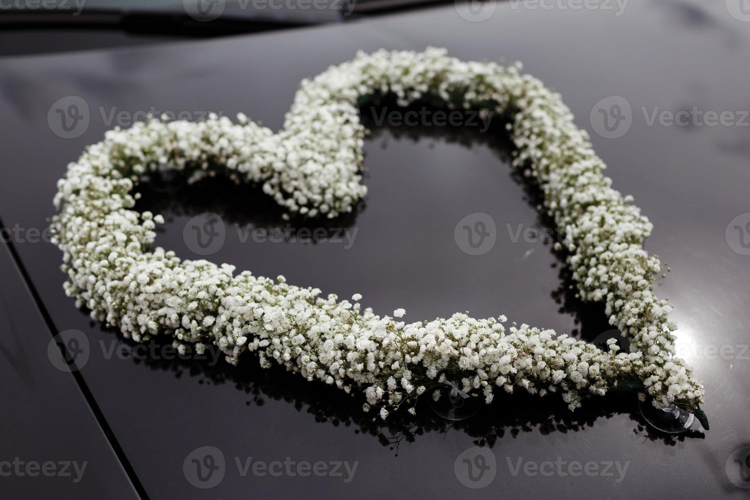 Coche de boda decorado con un corazón de flores blancas. foto