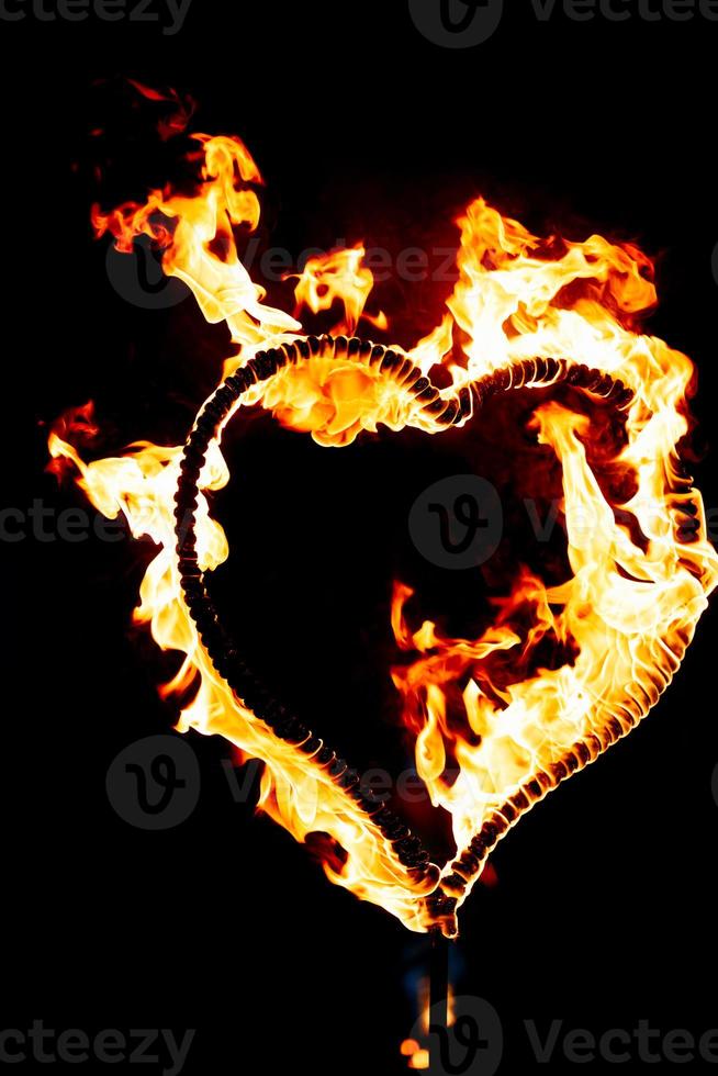 Burning heart with flames. Isolated on dark background. Fire show at night. Happy Valentine's Day card. Bengal fire burning heart. Space for text. Wedding or Valentine's concept. Happy new year. photo