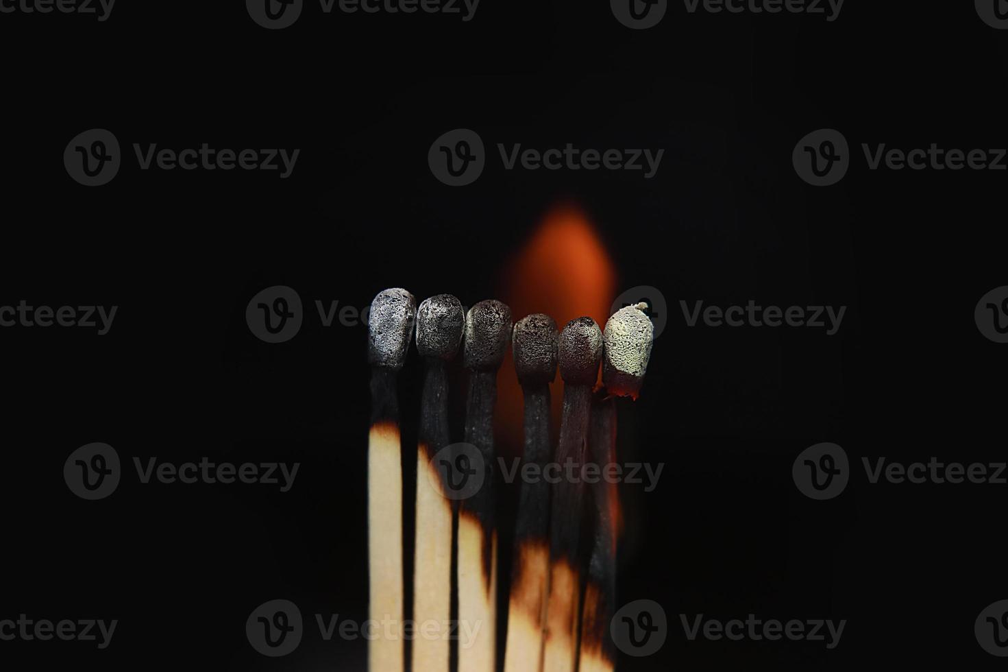 fósforos encendidos sobre fondo negro. fósforos encendidos en una fila de secuencia de quemado mientras un fósforo permanece alejado de la quema para evitar que el fuego se conecte contra un fondo negro. foto