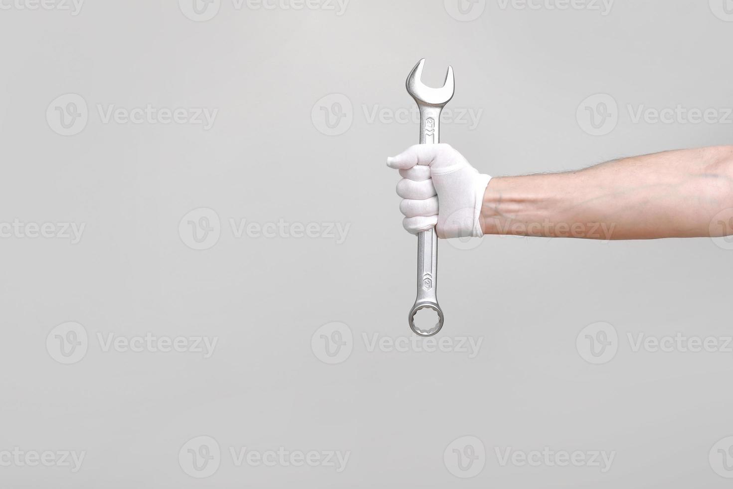 un trabajador, constructor, reparador, manitas, manos con guante de protección sosteniendo una llave sobre fondo blanco. espacio de copia de maqueta foto