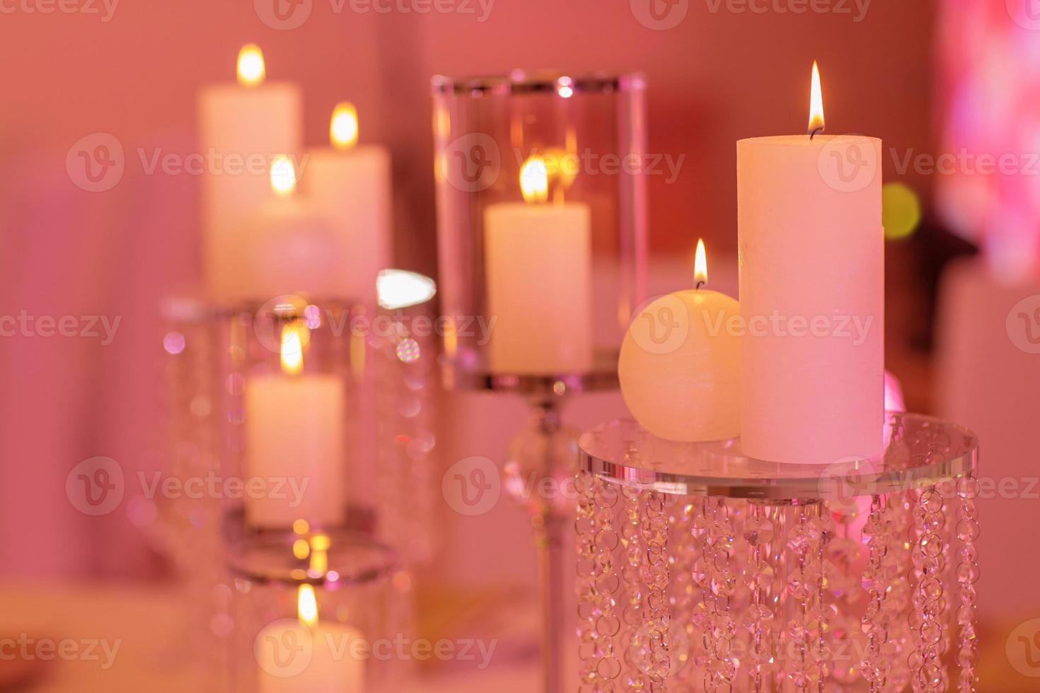 Burning candle in a round glass candlestick with decorative seashells. Candles on a glass candlestick photo