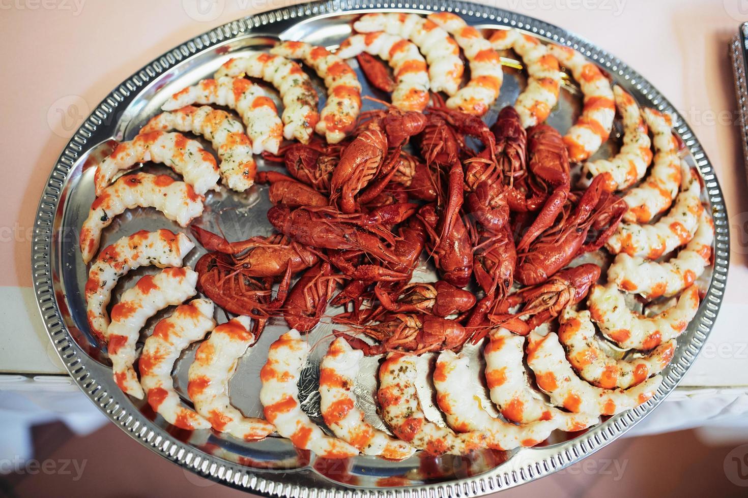 Mesa festiva con camarones y cangrejos de río con condimentos en una bandeja de metal foto