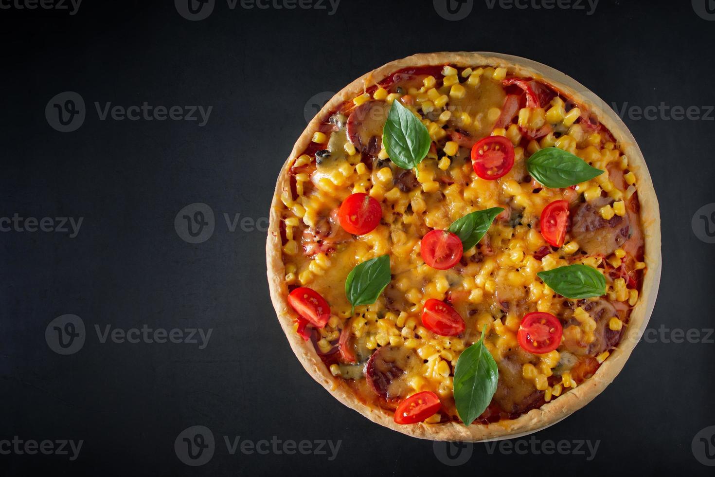 Big Italian pizza with tomatoes and basil on a black background photo