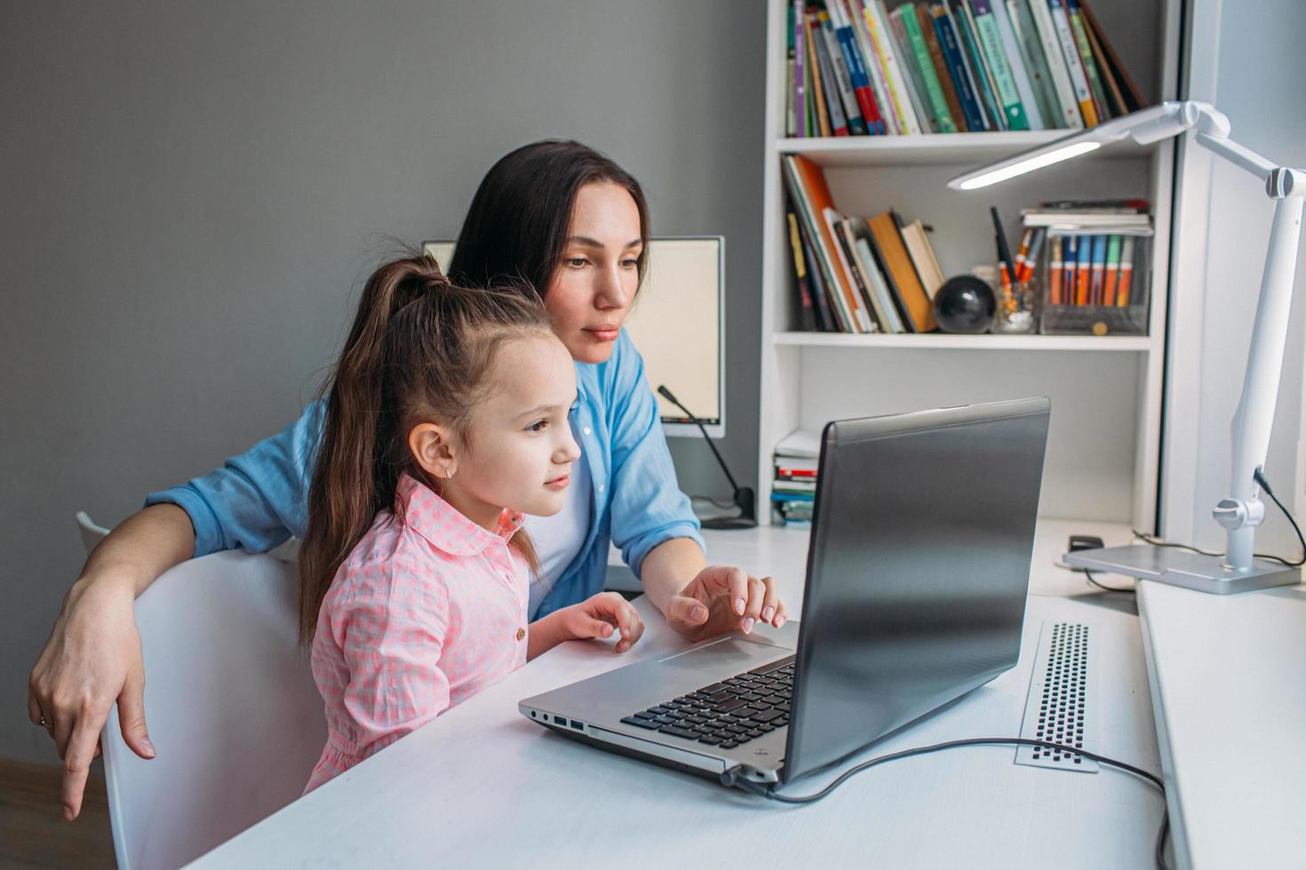 Mother assisting daughter with learning online photo