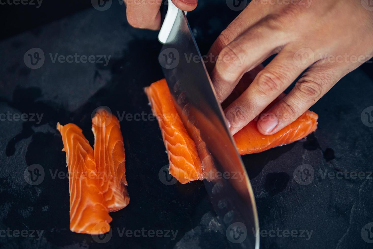 cortar salmón en una tabla de pizarra foto