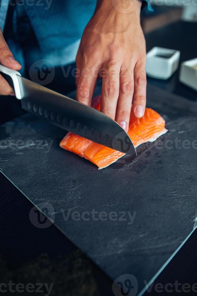 chef de sushi cortando salmón foto