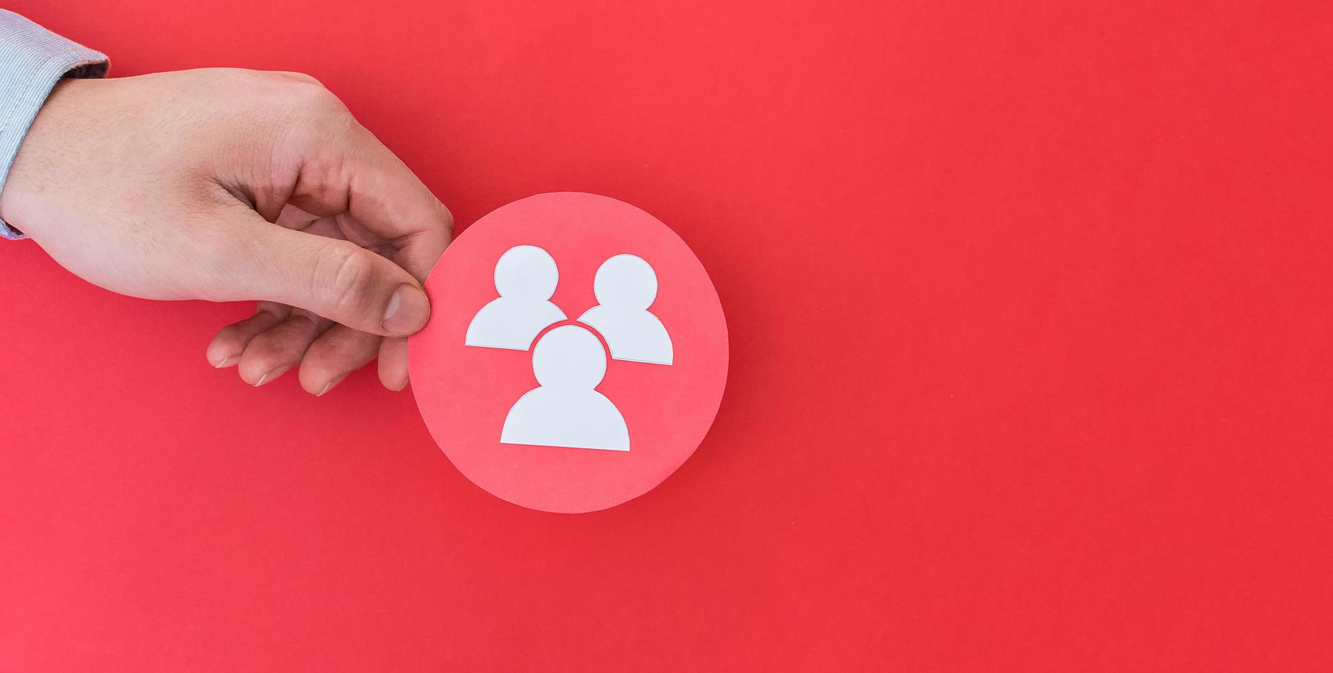 Male hand holding community shape symbol, on red background. photo