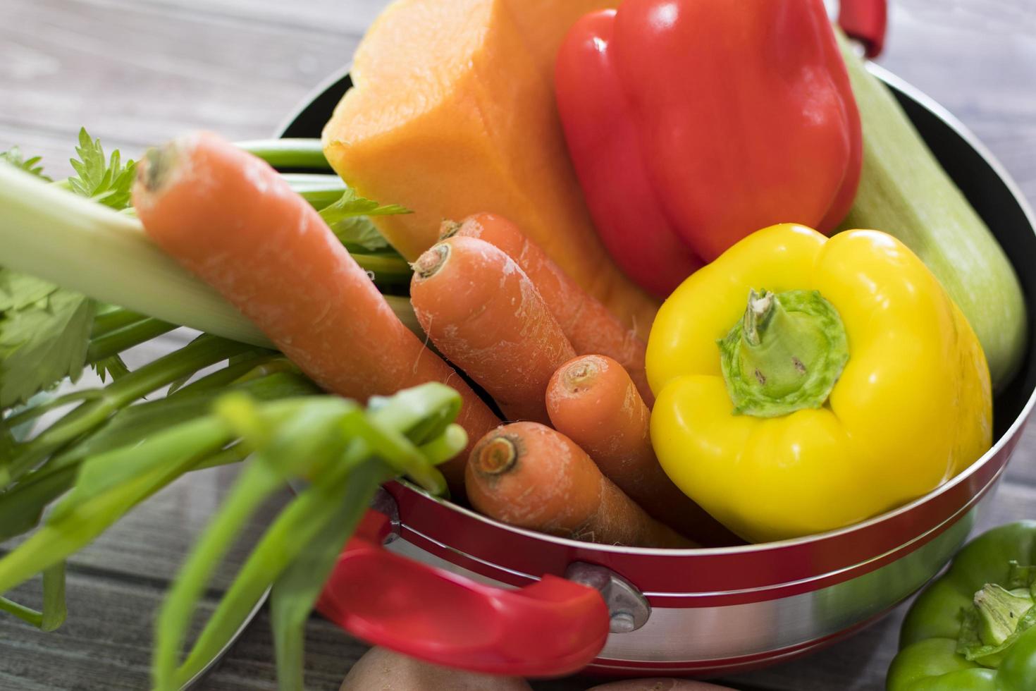 Cerrar verduras frescas para sopa en olla roja foto