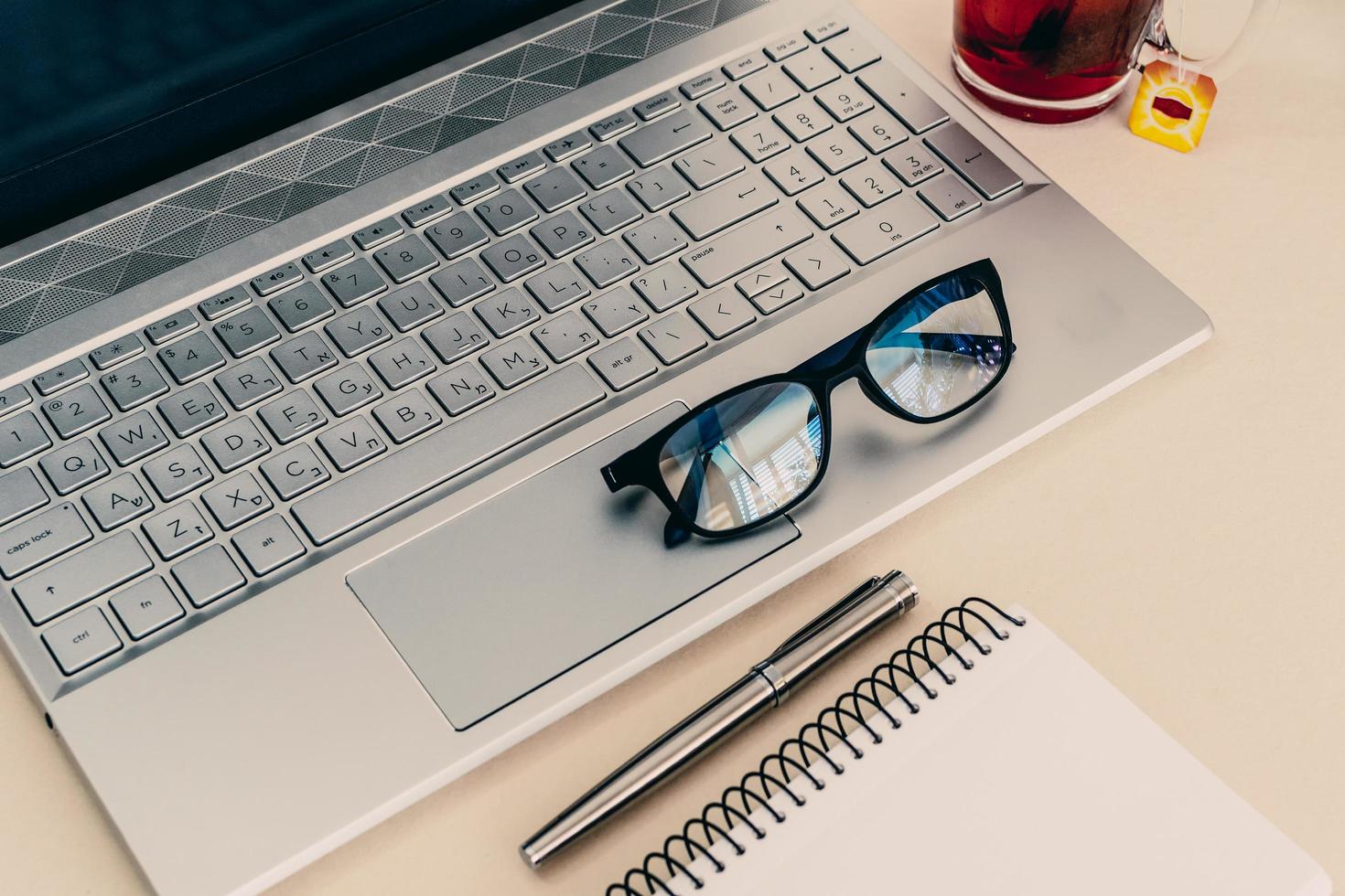 Business composition with laptop, glasses, fountain pen, and notebook on a work desk. photo