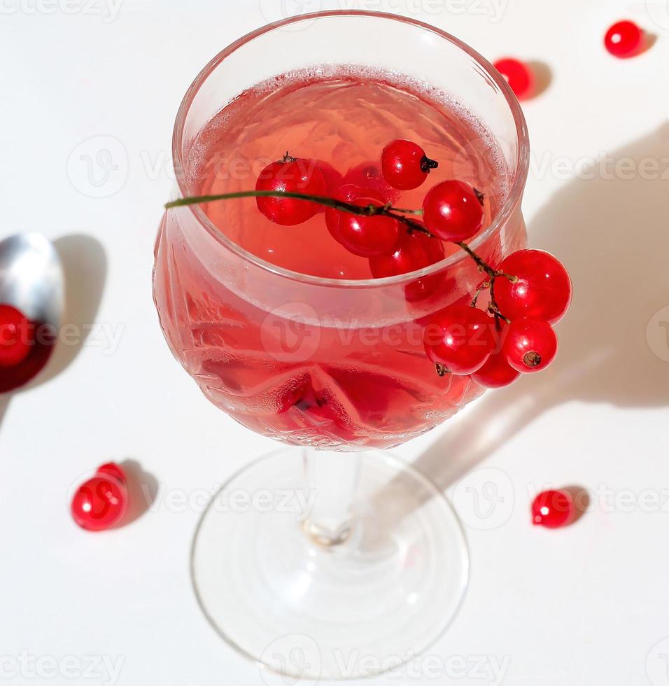 Pink champagne wine jelly with red currant in a glass, bright daylight, on white background. Top view. Copy space photo