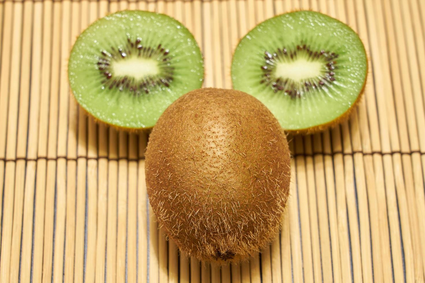 Ripe brown kiwi with cut green kiwi on a straw background with space for text. photo