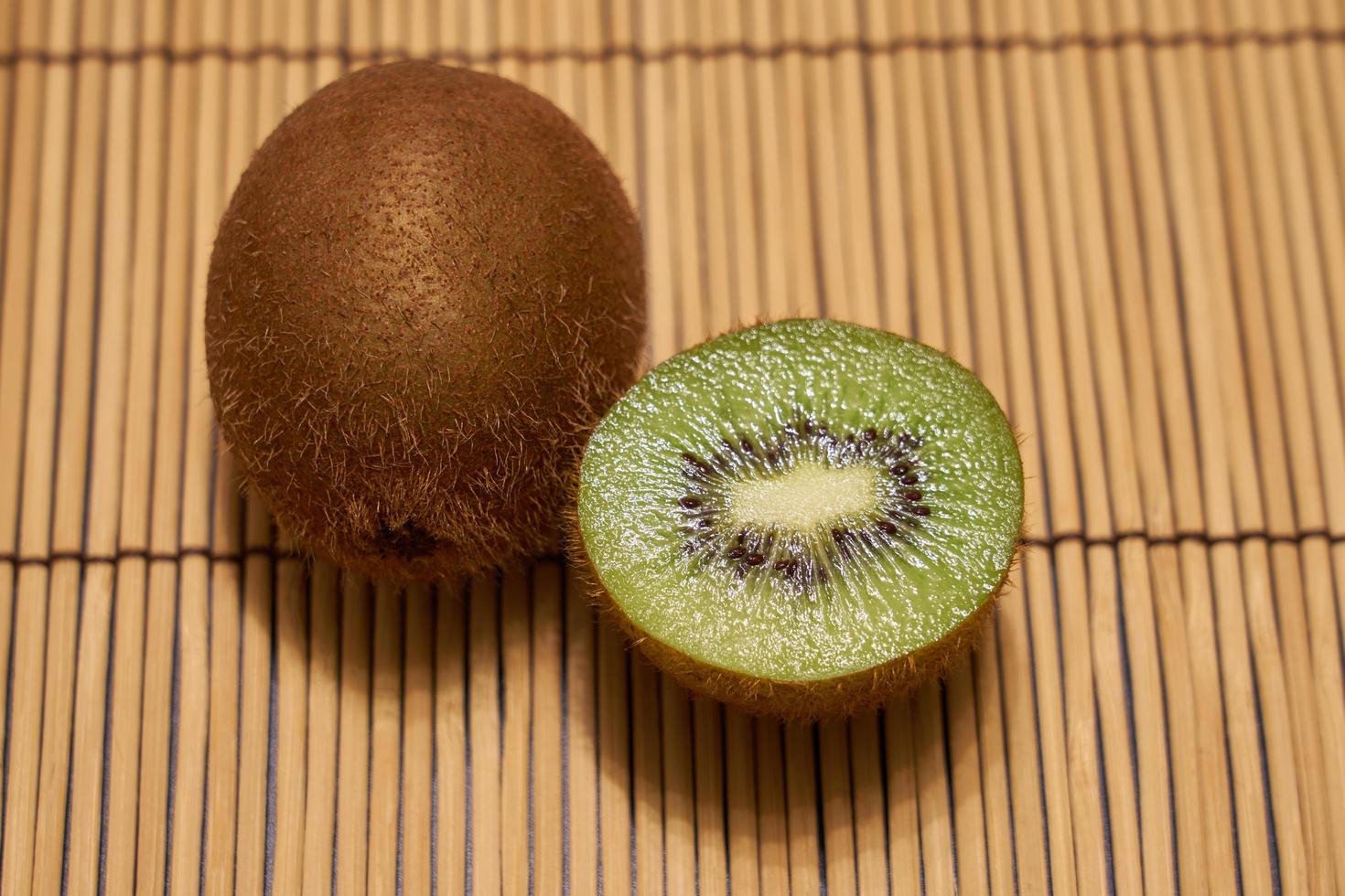 Ripe brown kiwi with cut green kiwi on a straw background with space for text. photo