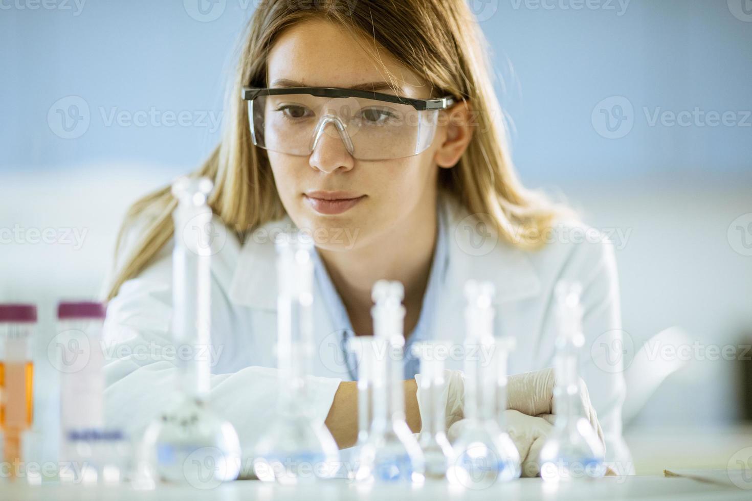 Investigadora científica o médica femenina mirando frascos con soluciones en un laboratorio foto