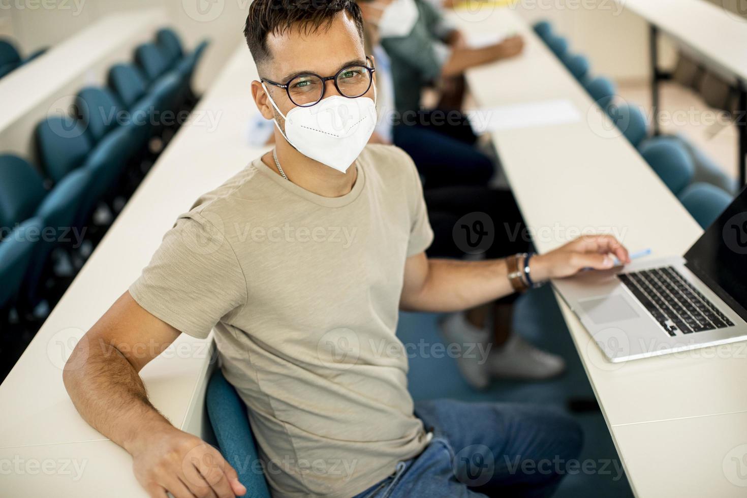 Estudiante masculino con máscara médica protectora facial para protección contra virus en la sala de conferencias foto