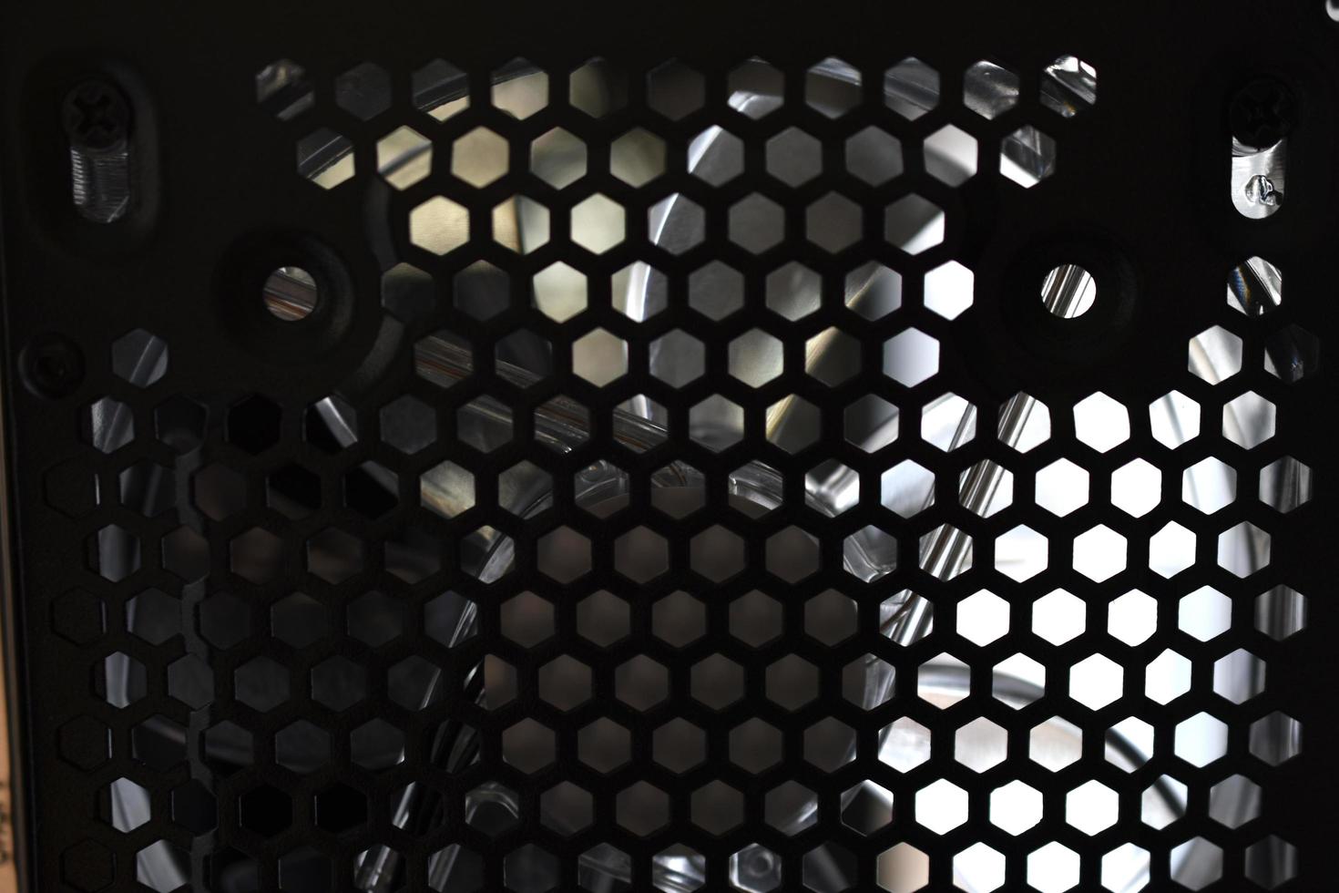 Black computer fan behind a grid with wires photo
