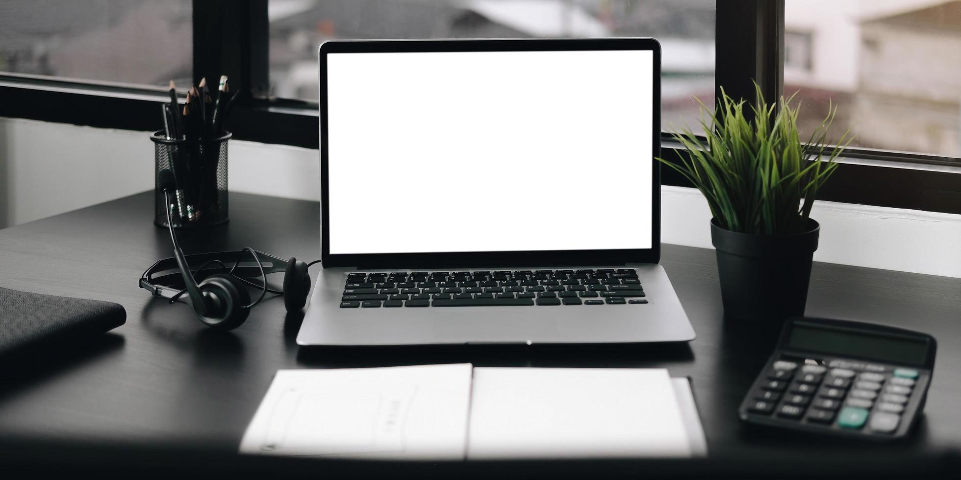 Laptop on desk mock-up with notebook and calculator photo