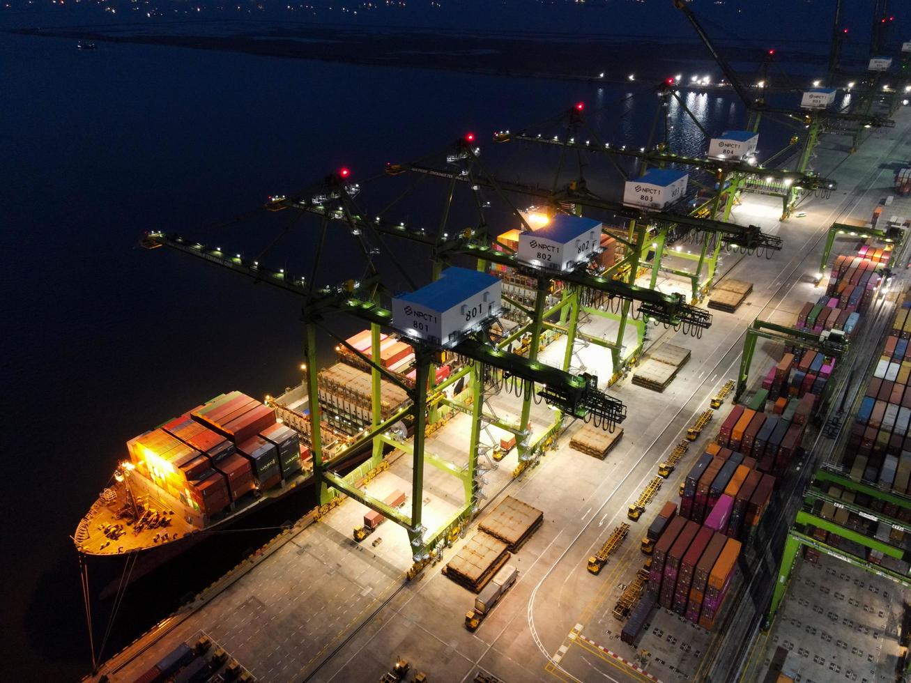 Jakarta, Indonesia 2021- Aerial view of Container ship loading and unloading in deep sea port, logistic import and export freight transportation by container ship in open sea at night photo