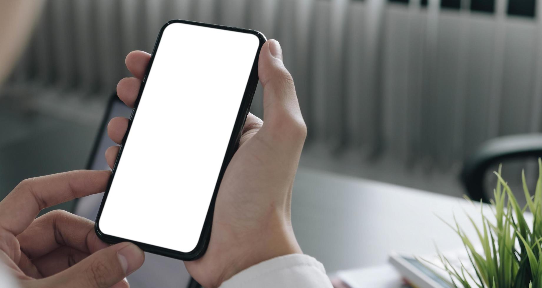 Person holding a smartphone at a desk mock-up photo