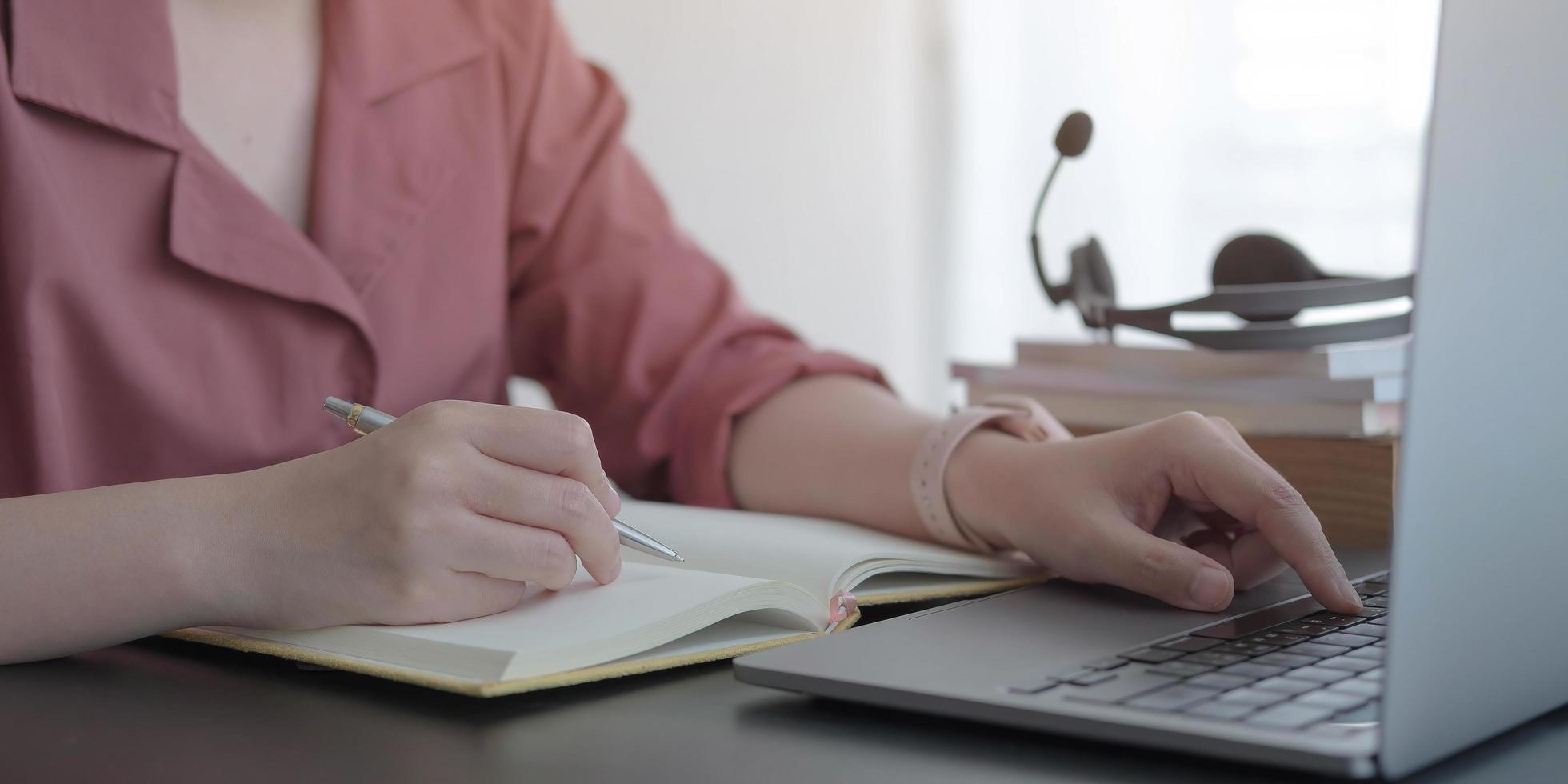 notas de escritura profesional mientras usa la computadora portátil foto