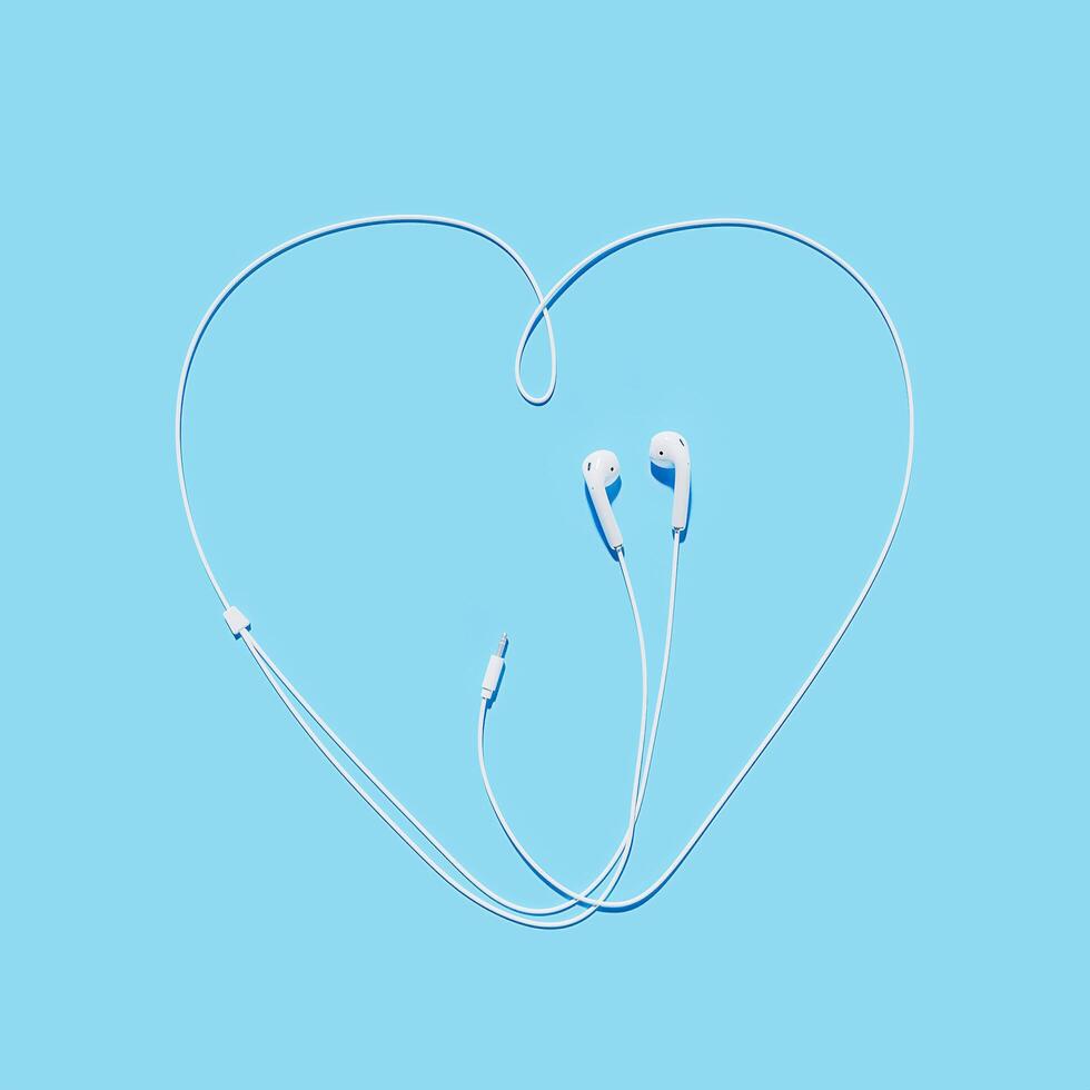 Auriculares con el cable haciendo la forma de un corazón sobre fondo azul, representación 3d foto