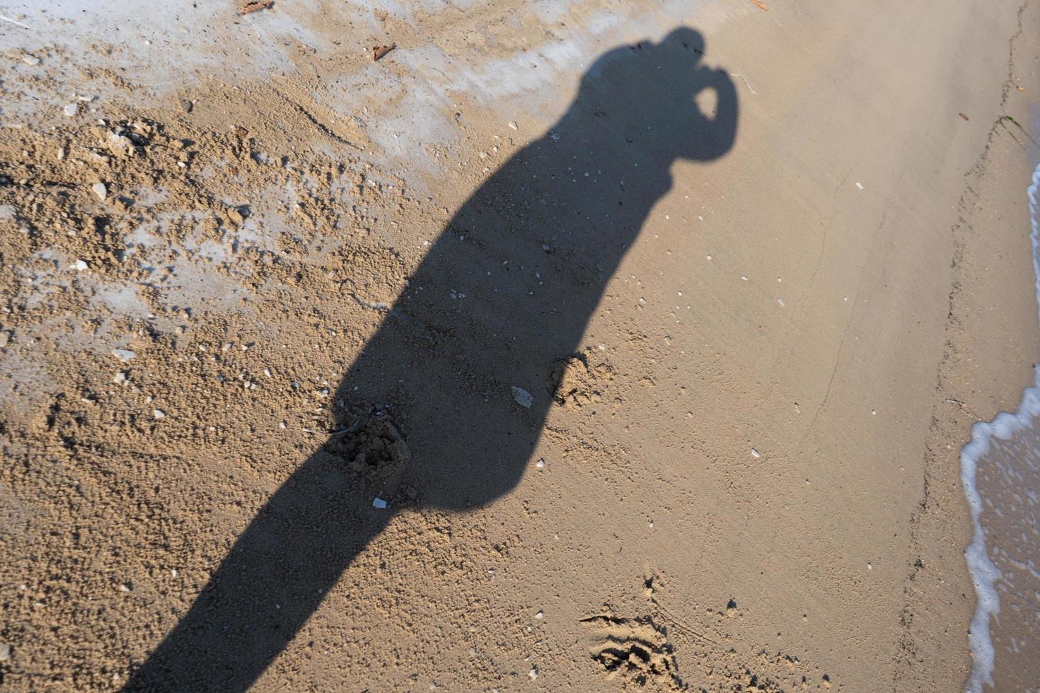 Silhouette of a person taking a photograph at the beach photo