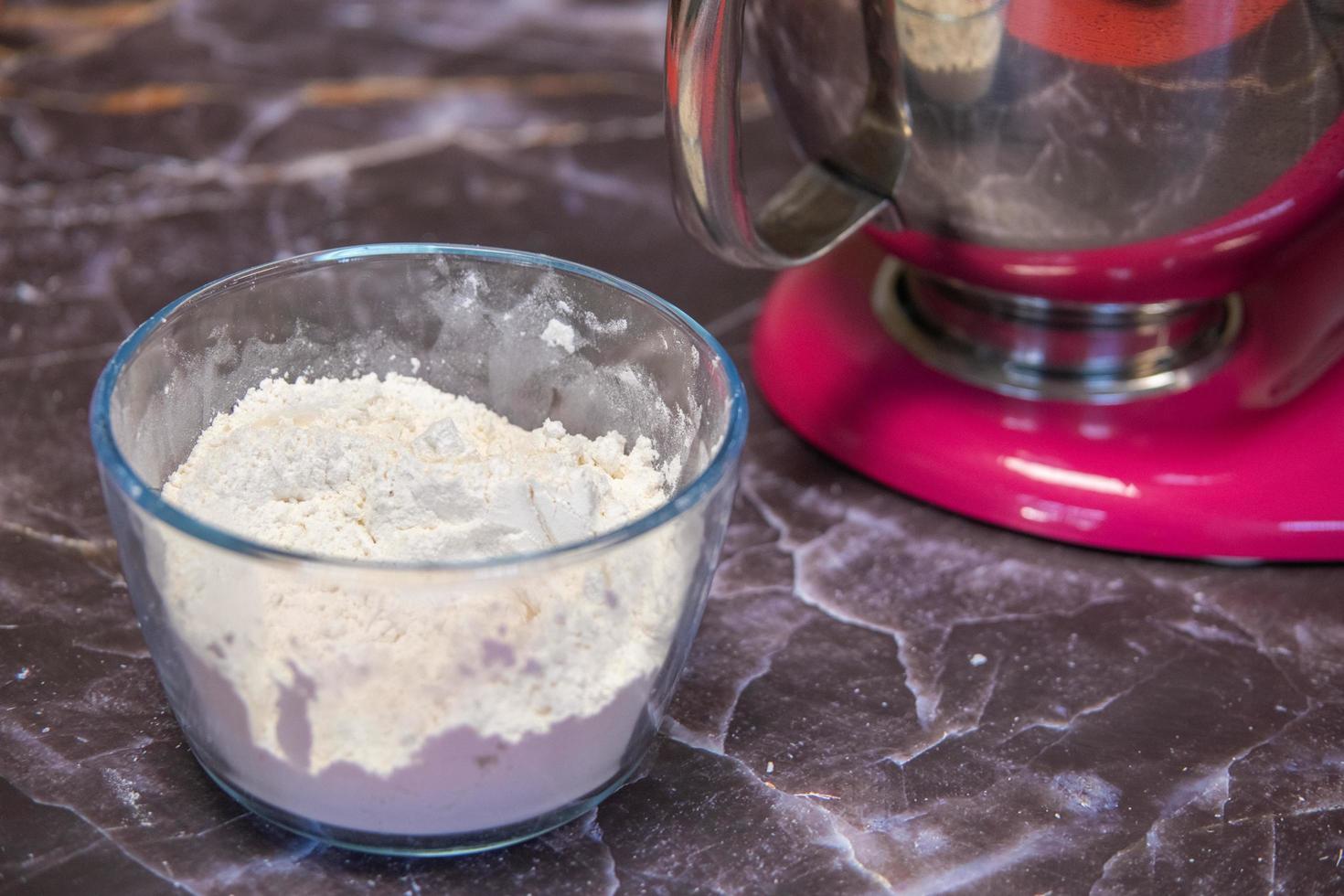 Bowl of flour next to a large mixer on a dark marble background photo