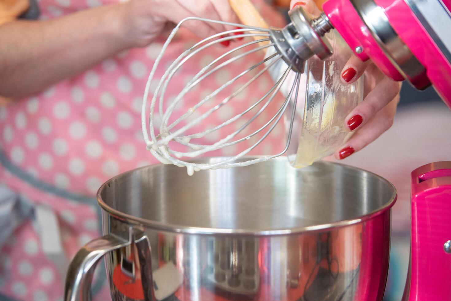 Woman in a pink apron using a big mixer photo