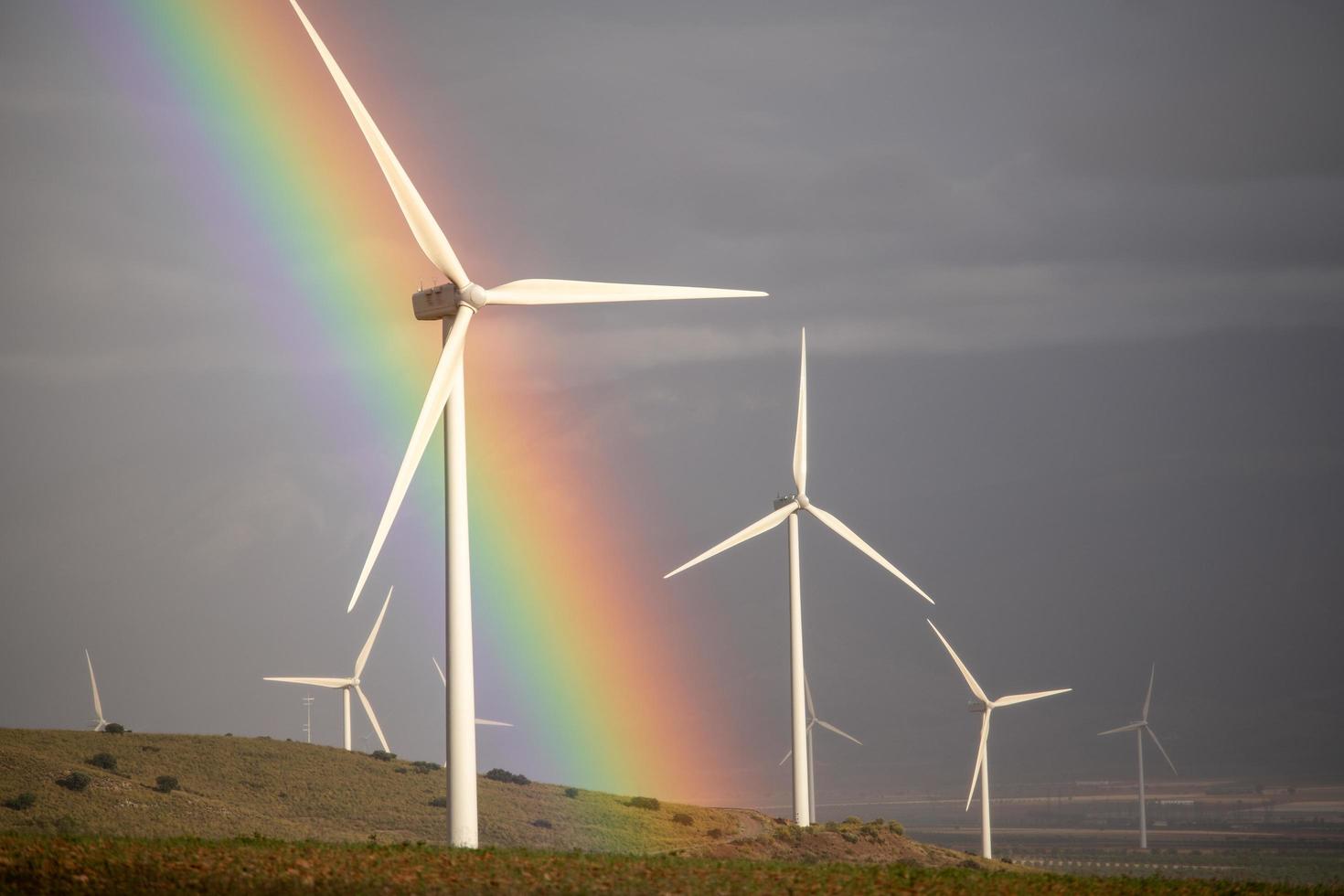 Wind power mills in a storm with cloudy gray skies and a rainbow photo