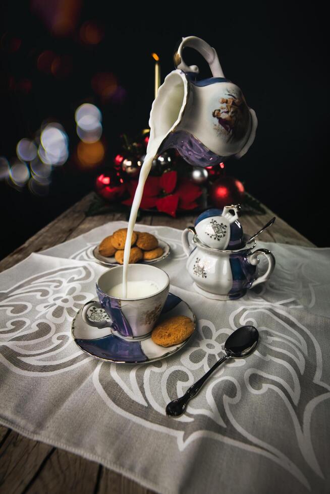 Juego de té antiguo con galletas y leche cayendo foto