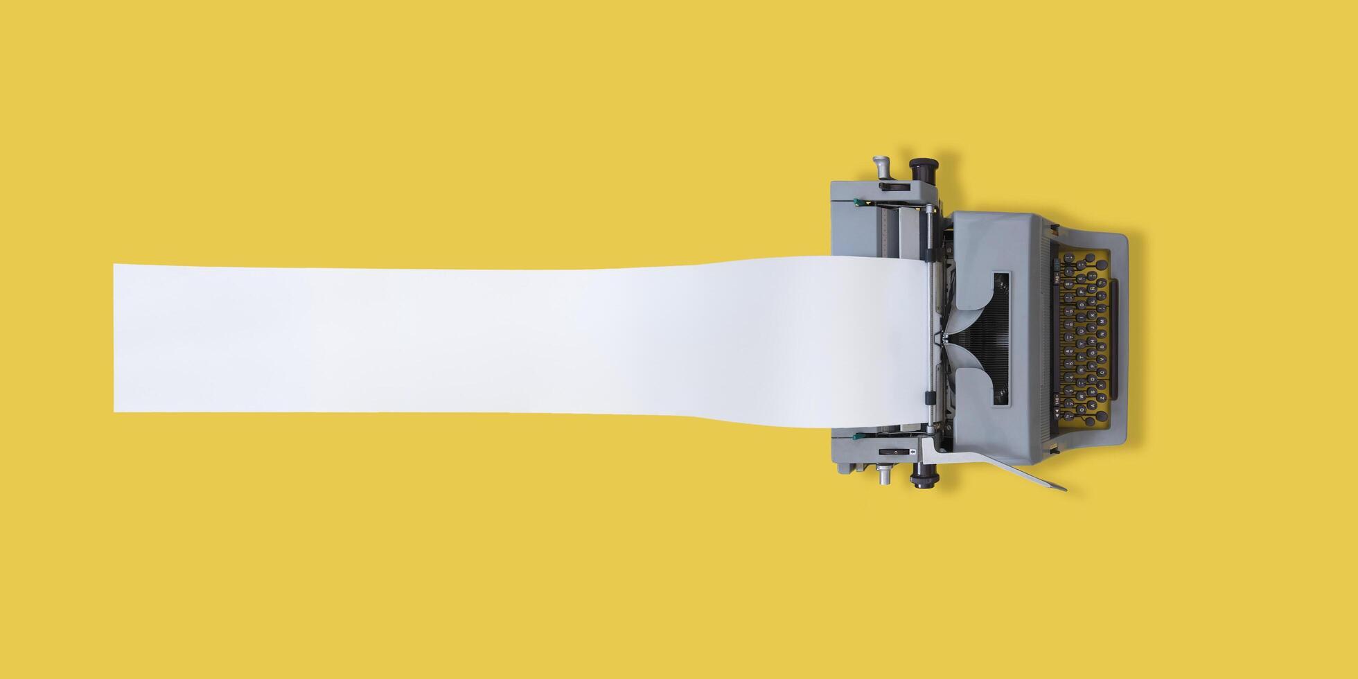 Old typewriter with very long paper and yellow background with space