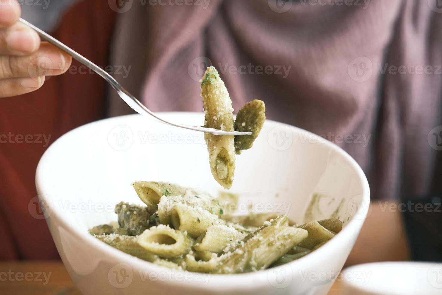 Person eating penne pasta photo