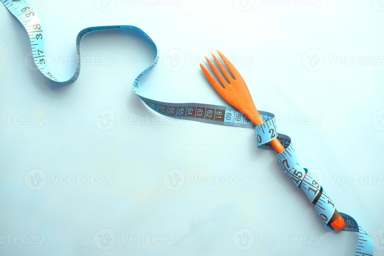 Fork with measurement tape on blue background photo