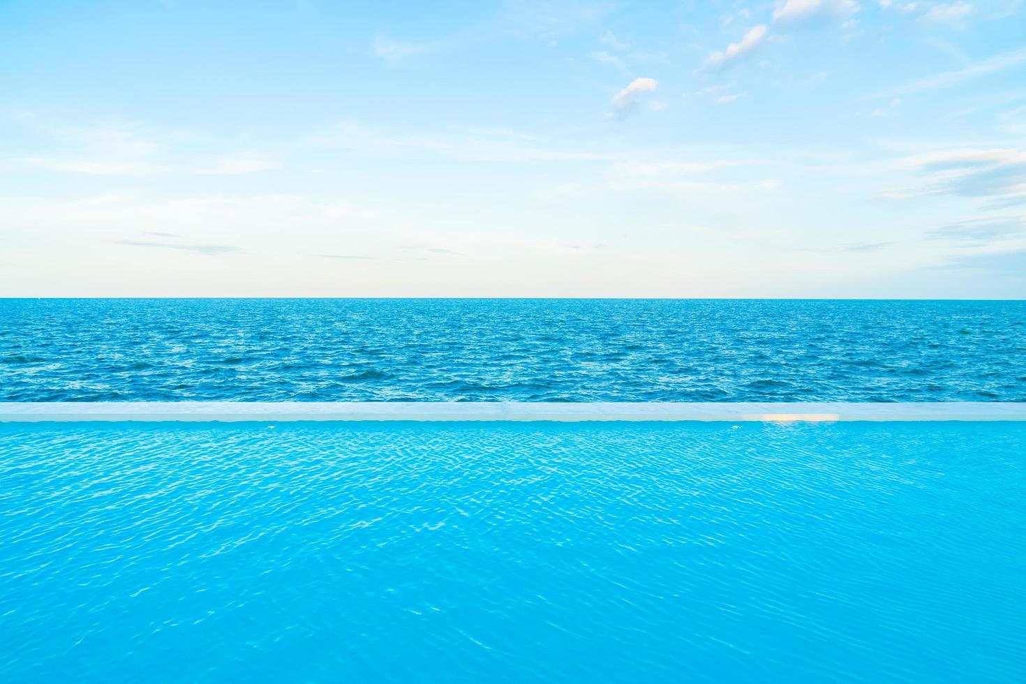 Infinity swimming pool with sea and ocean view on blue sky photo