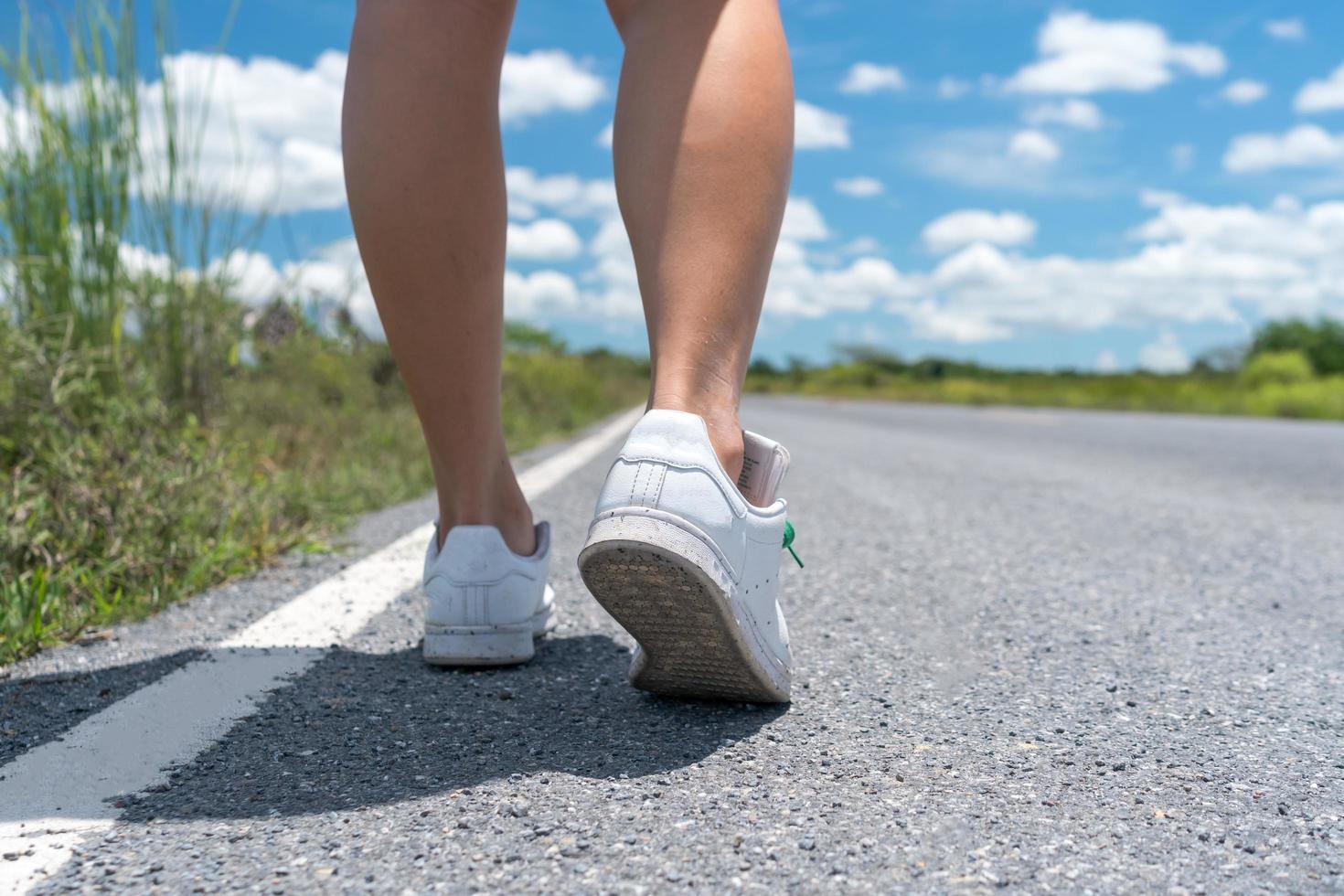 Woman walking on small country road with blue sky background photo