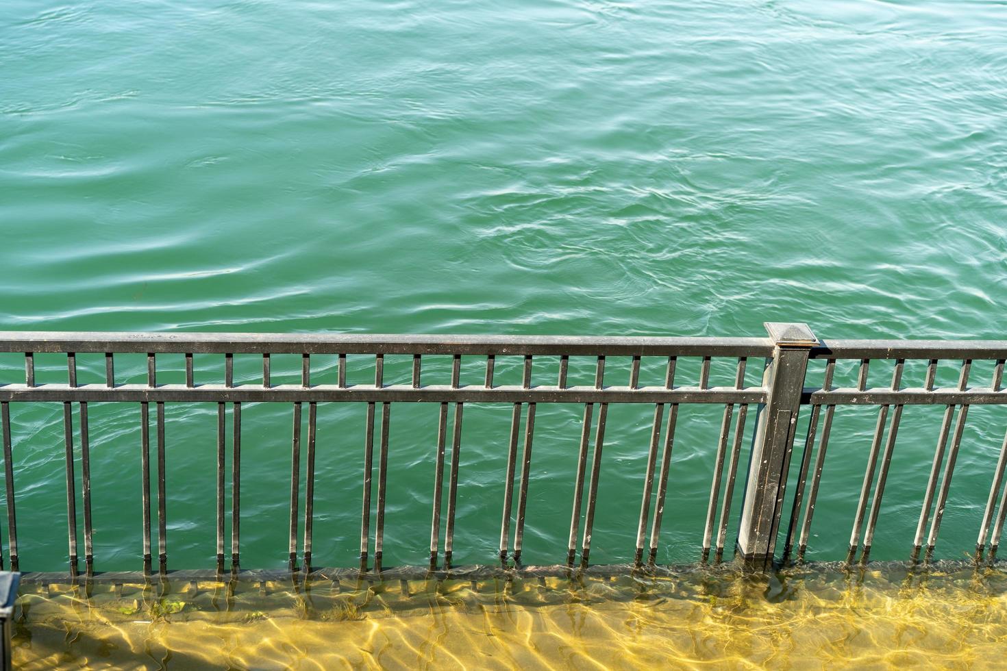 Flooded embankment next to a metal fence at the Angara River in Irkutsk photo