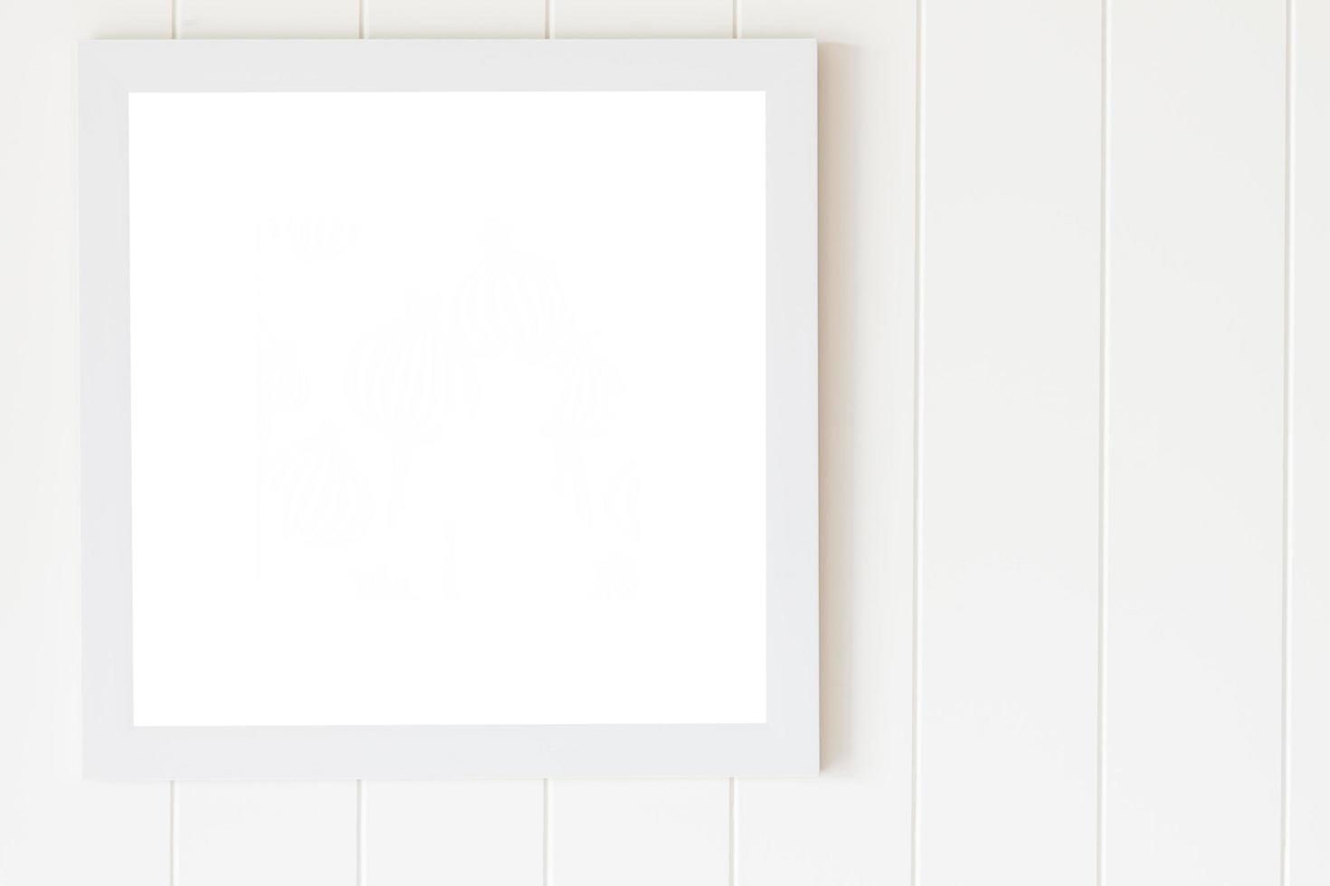 Blank photo frame on white wood wall background