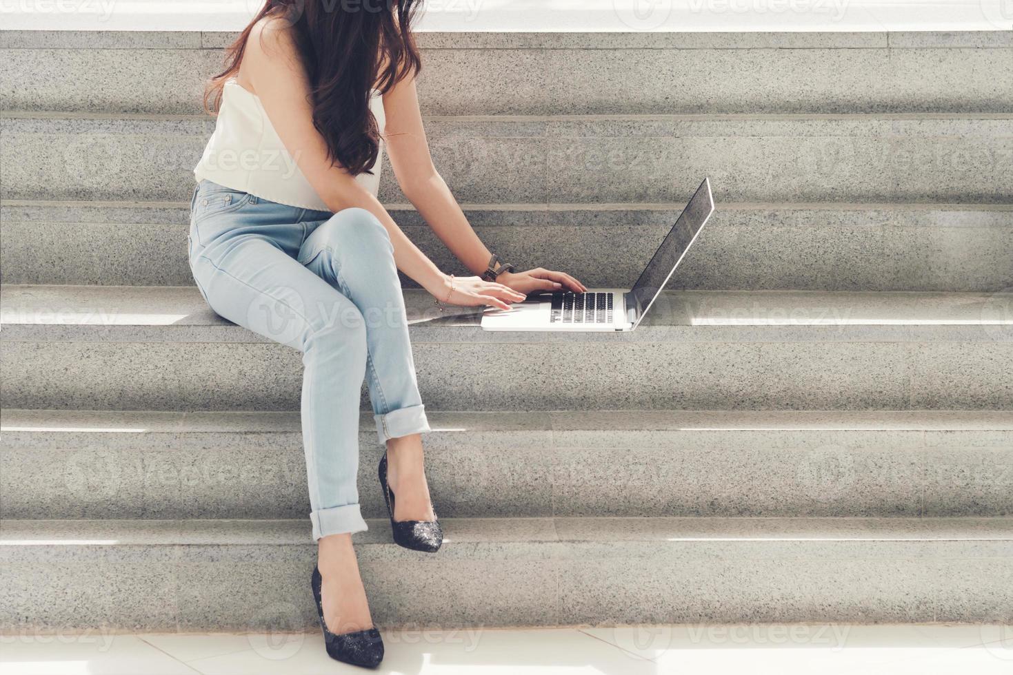 mujer trabajadora usa una computadora sentada en las escaleras foto