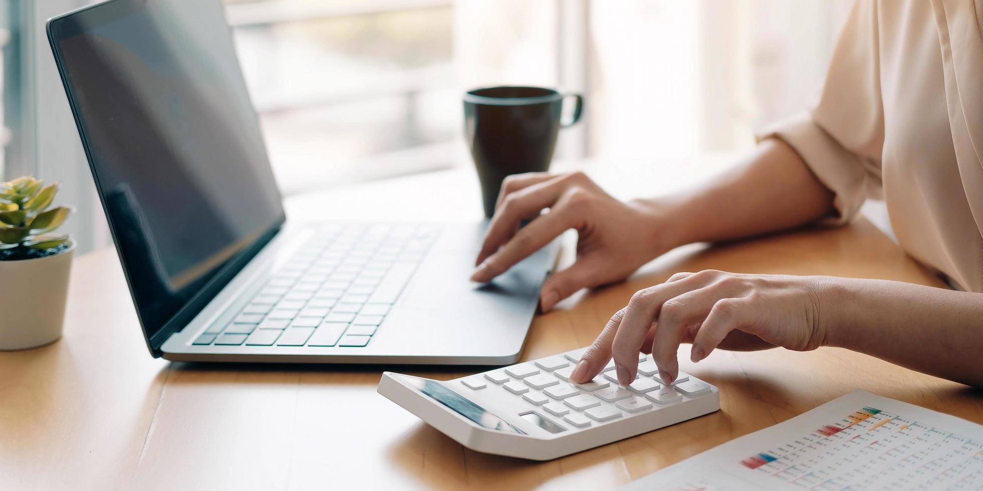 Person working on a calculator and laptop photo