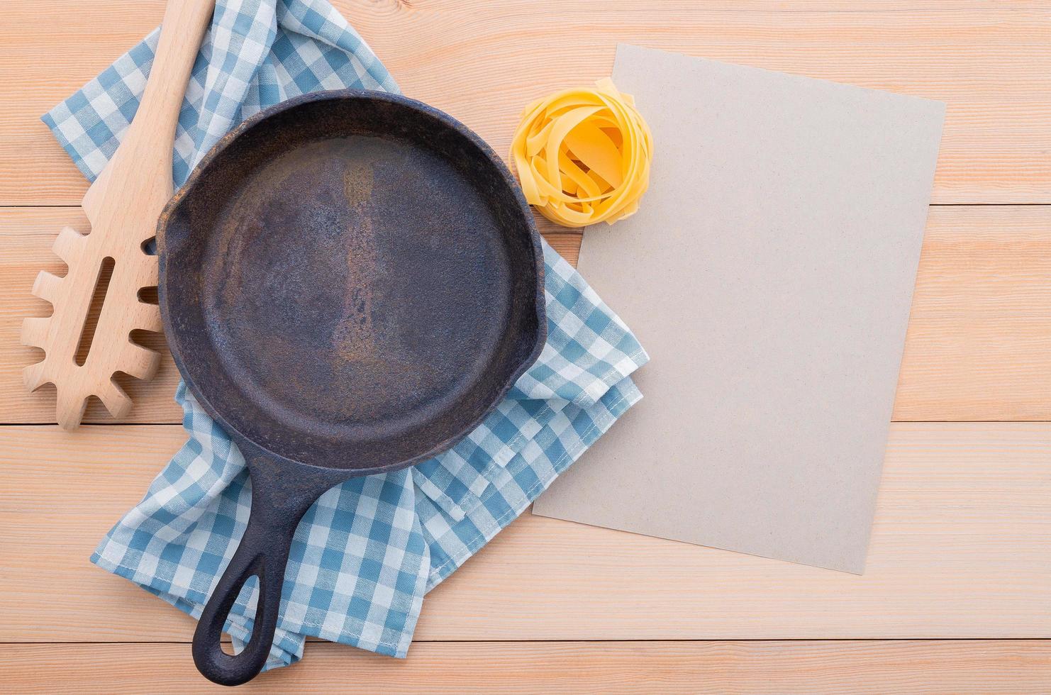 Food background for tasty Italian dishes with empty cast iron skillet and pasta ladle photo