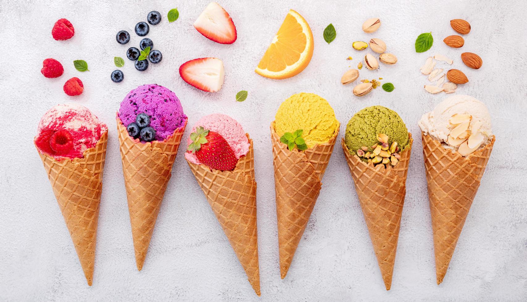 Various of ice cream flavors in cones on white stone background photo