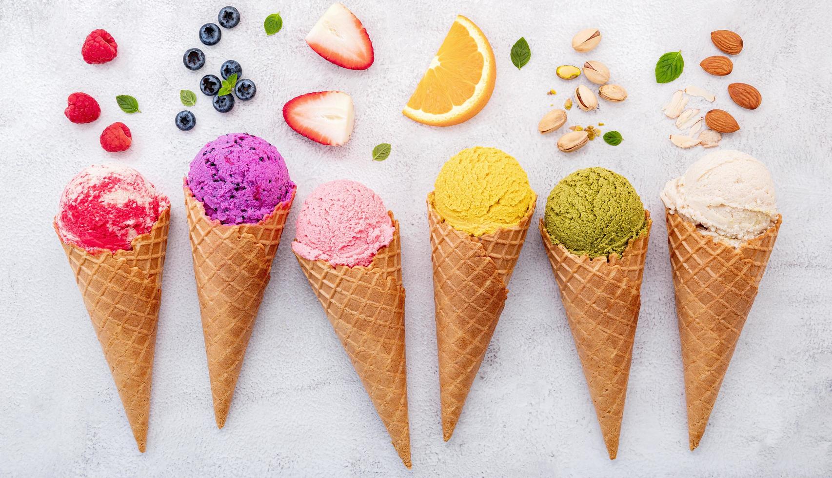 Various of ice cream flavors in cones on white stone background photo