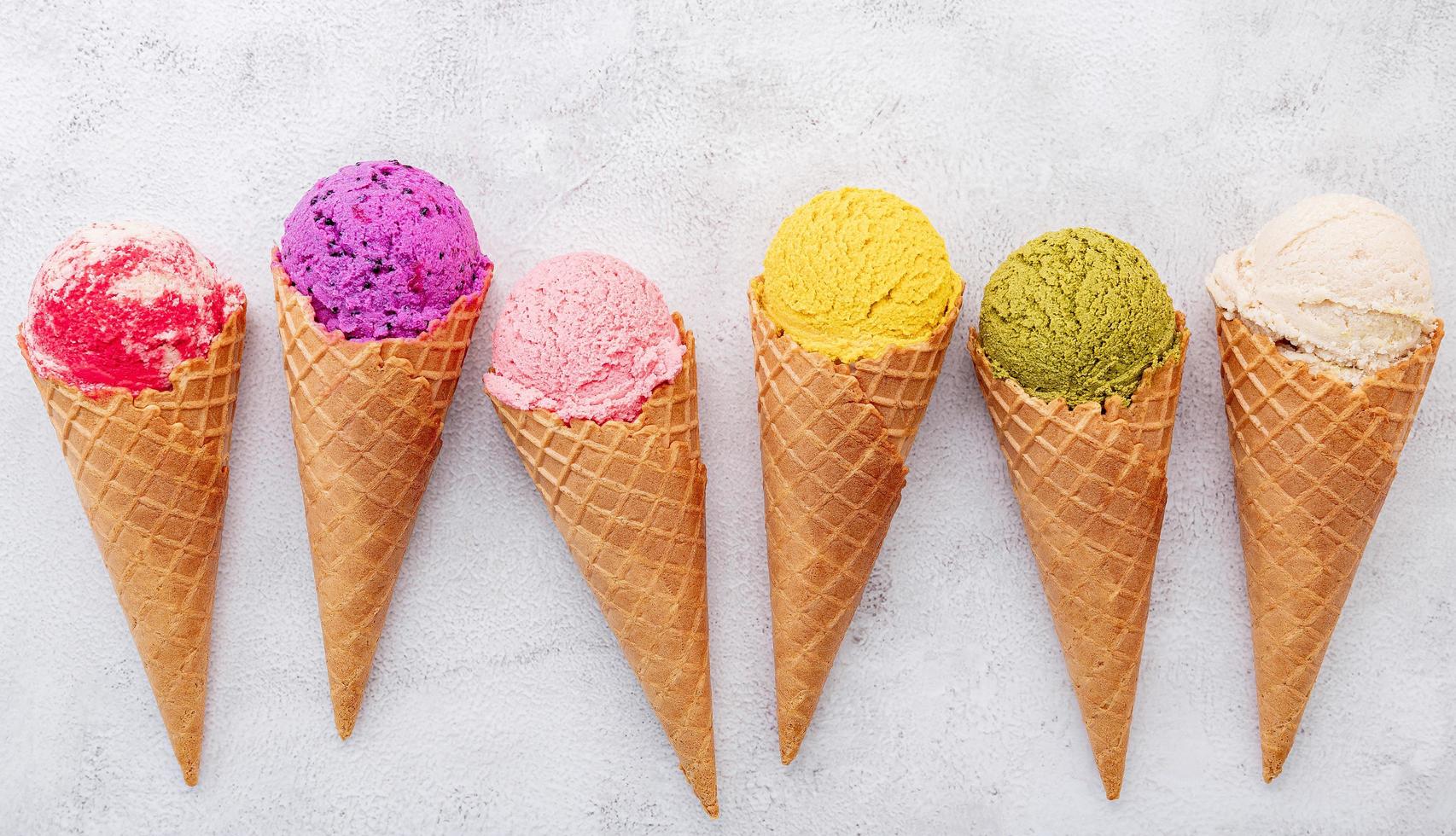 Various of ice cream flavors in cones on white stone background photo