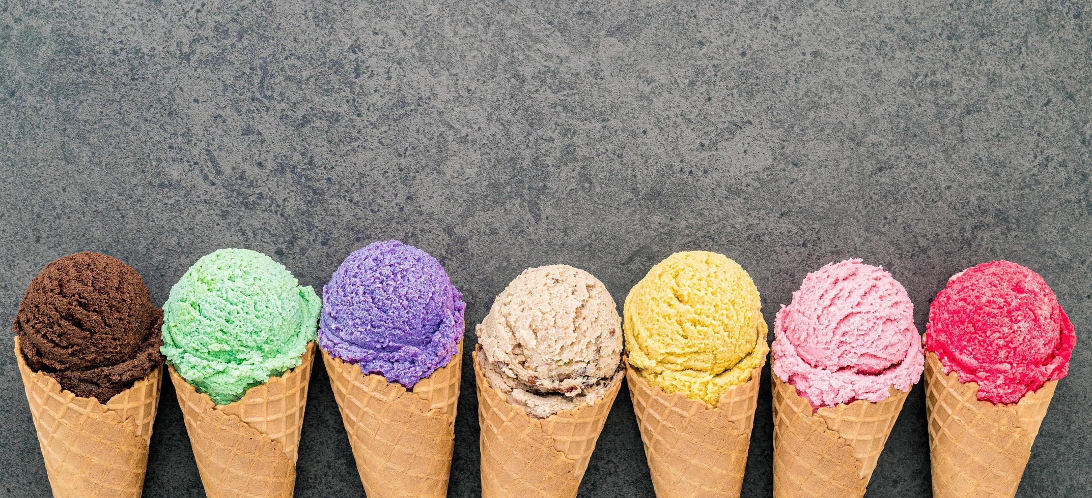 Flat lay various of ice cream cones set up on dark stone background photo