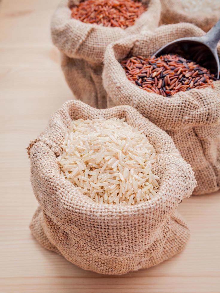 Mixed whole grain traditional thai rices in hemp sacks bag setup on wooden background photo