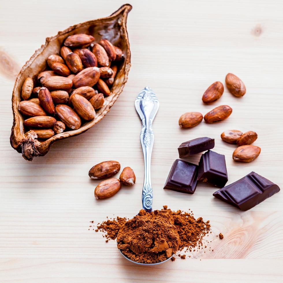 Roasted cocoa beans and dark chocolate setup on wooden background photo